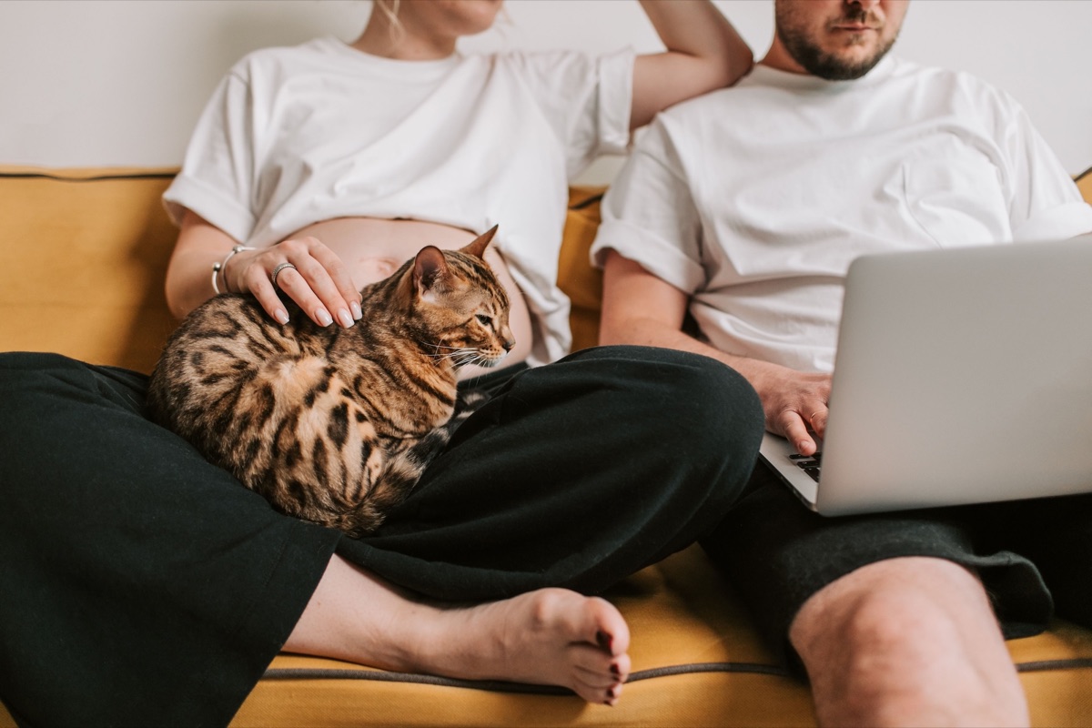 Pregnant person and partner sitting together with a laptop