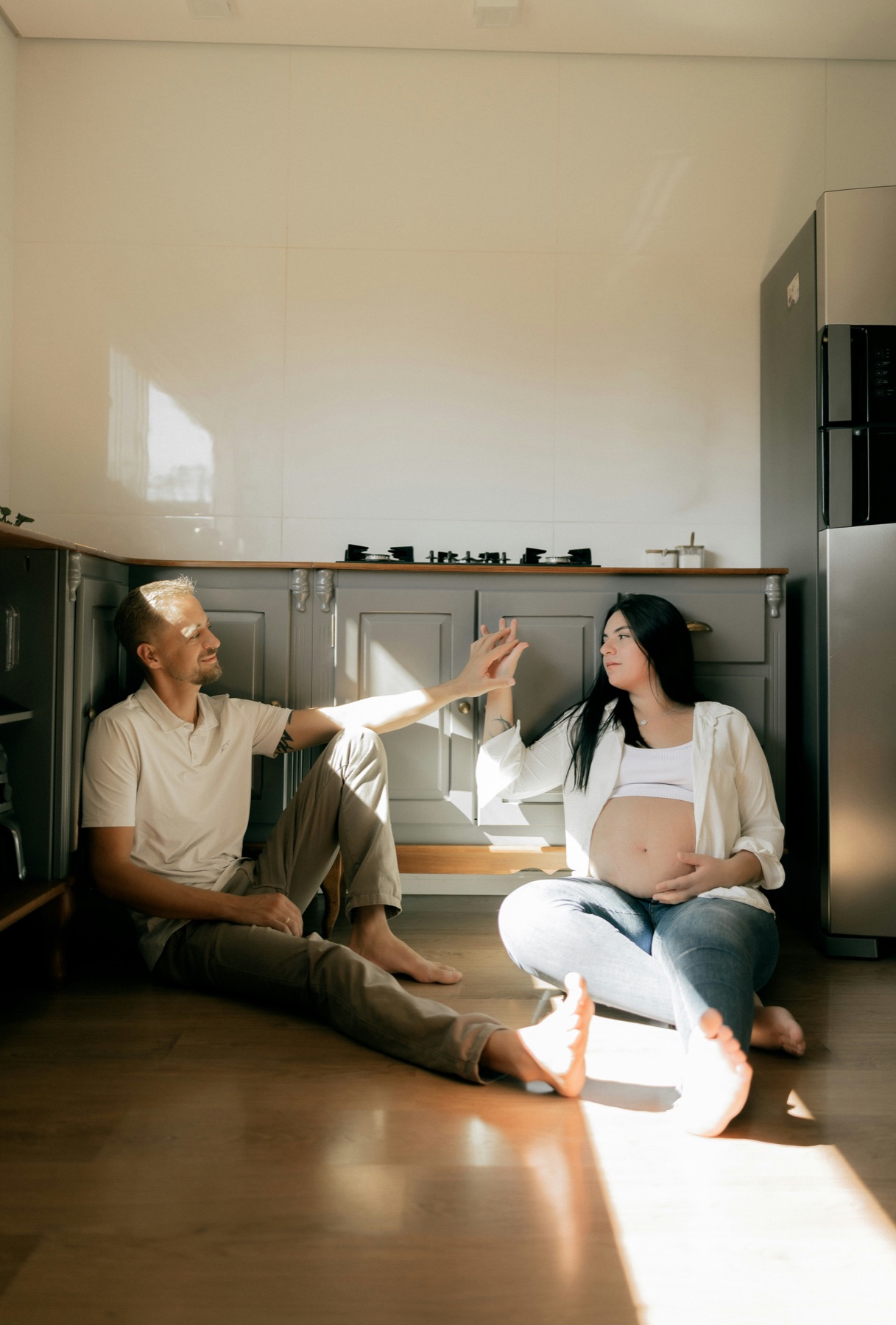 Pregnant couple sitting together in a sunlit kitchen